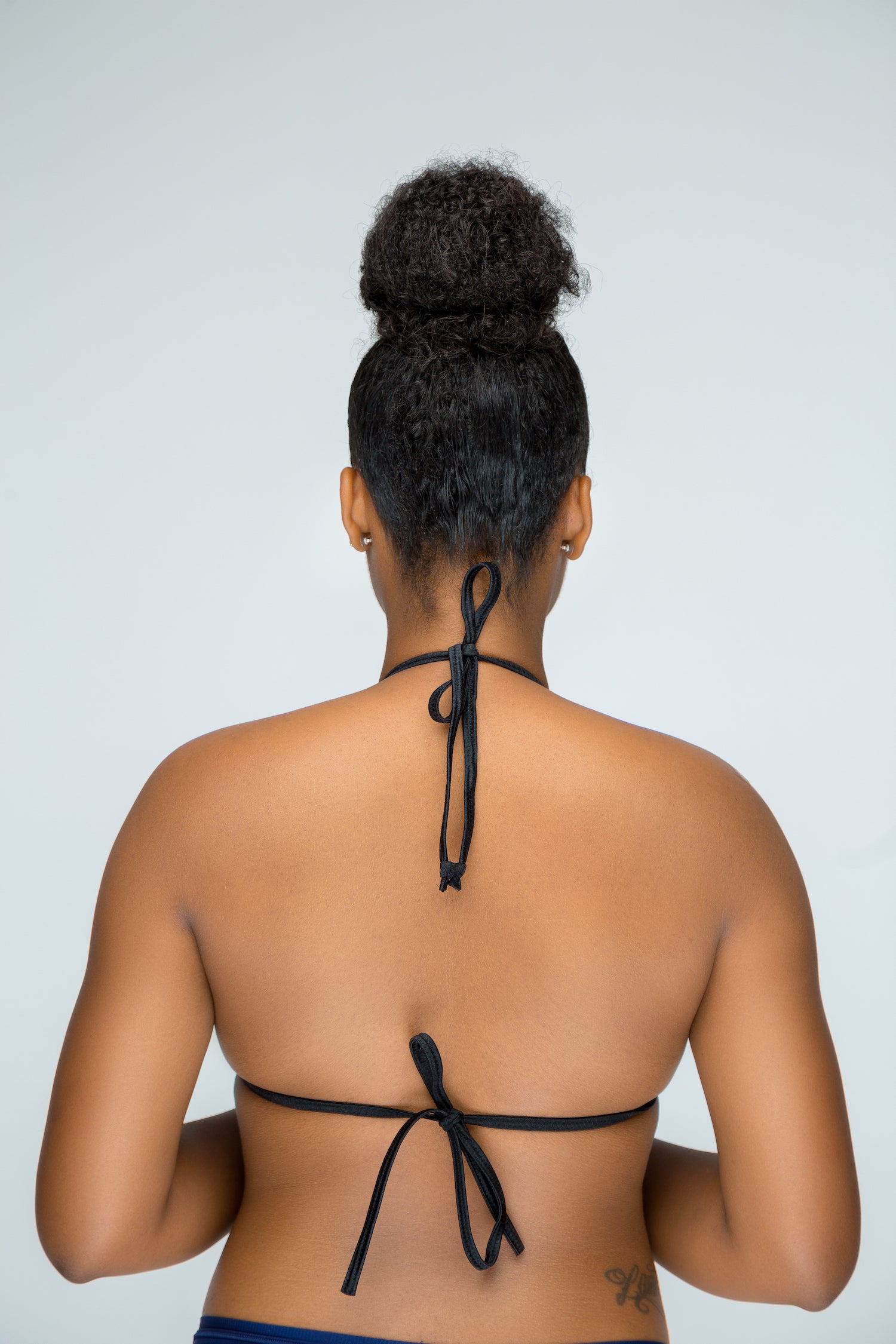 a woman wearing a bikini top with a tie around her neck